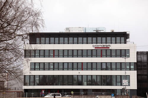 Moderner mehrstöckiger Büro- und Produktionsbau von Systemceram mit breiten Fensterfronten an einer Straße an einem grauen Wintertag