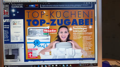 Werbeanzeige auf einem Computerbildschirm mit lachender Frau hinter aufgestapelten Tellern vor einem Miele-Geschirrspüler und großem Schriftzug „Top-Küchen! Top-Zugabe!“