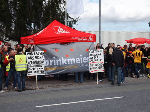 Gewerkschaftlich organisierte Mitarbeiter demonstrieren vor einem roten IG-Metall-Zelt mit Transparenten und Schildern gegen Stellenabbau und Geschäftsentscheidungen bei Brinkmeier Küchen