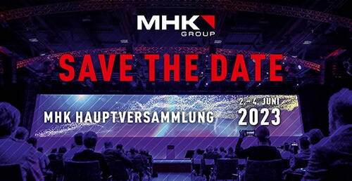 Publikumsveranstaltung in großer, blau-violett beleuchteter Konferenzhalle mit Hinweis „Save the Date“ zur MHK Hauptversammlung vom 2. bis 4. Juni 2023 auf einer breiten Leinwand