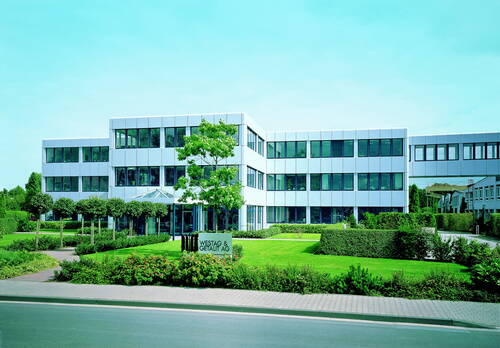 Modernes Bürogebäude der Westag & Getalit AG mit großer Glasfassade, gepflegtem Vorgarten und breiter Zufahrt an einer ruhigen Straße.