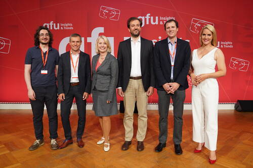 Sechs lächelnde Konferenzteilnehmerinnen und -teilnehmer stehen nebeneinander auf einer Bühne vor einer roten „gfu Insights & Trends“-Rückwand.