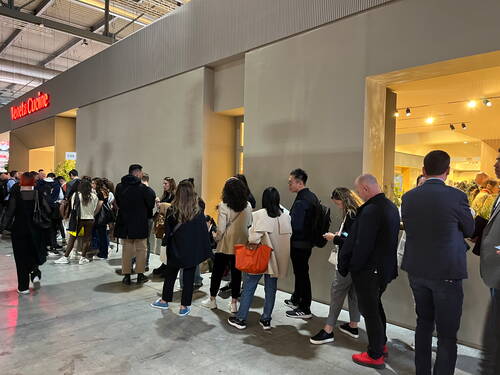 Lange Besucherschlange vor dem Eingang eines gut beleuchteten Messestands von Veneta Cucine in einer großen Ausstellungshalle