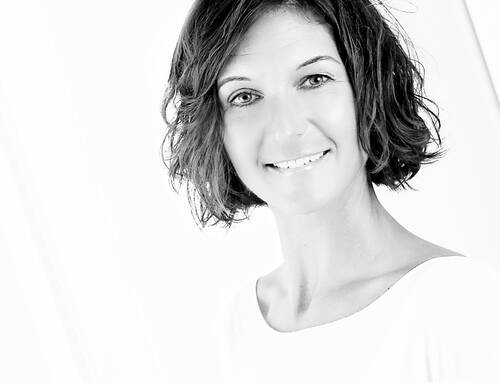 Lächelnde Frau mit kurzen, leicht gewellten Haaren in einem hellen, minimalistischen Schwarz-Weiß-Porträt
