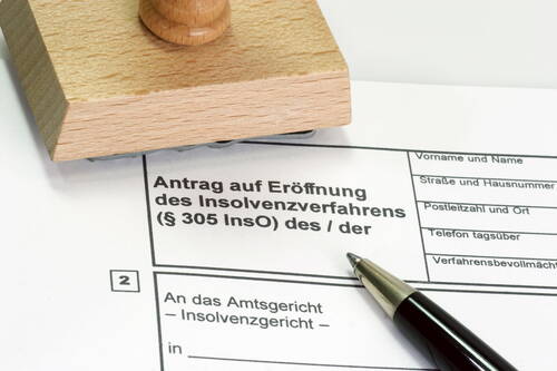 Ausgefüllter Antrag auf Eröffnung eines Insolvenzverfahrens mit Kugelschreiber und Holzstempel auf dem Formular