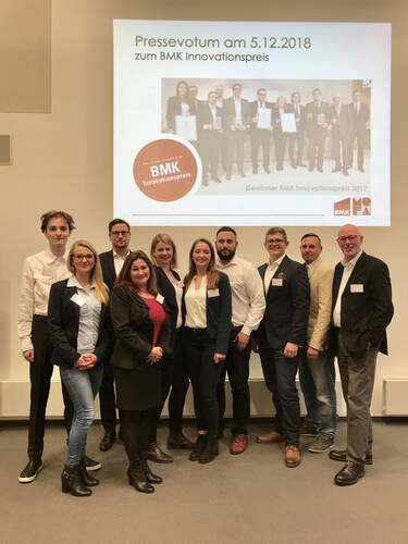 Gruppenfoto von elf Geschäftsleuten vor einer Leinwand mit Präsentation zum BMK Innovationspreis 2018