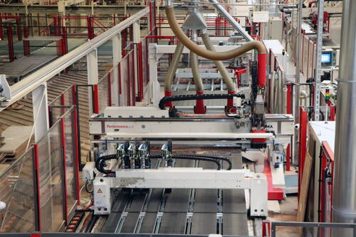 Automatisierte CNC-Holzbearbeitungsanlage mit mehreren Fräsköpfen und Absaugschläuchen in einer modernen Produktionshalle